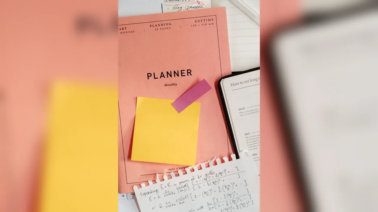 An open planner notebook beside a laptop and a cup of coffee on a white desk
