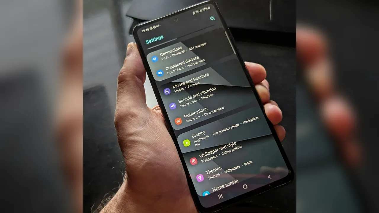 A hand holding a phone open on its settings menu